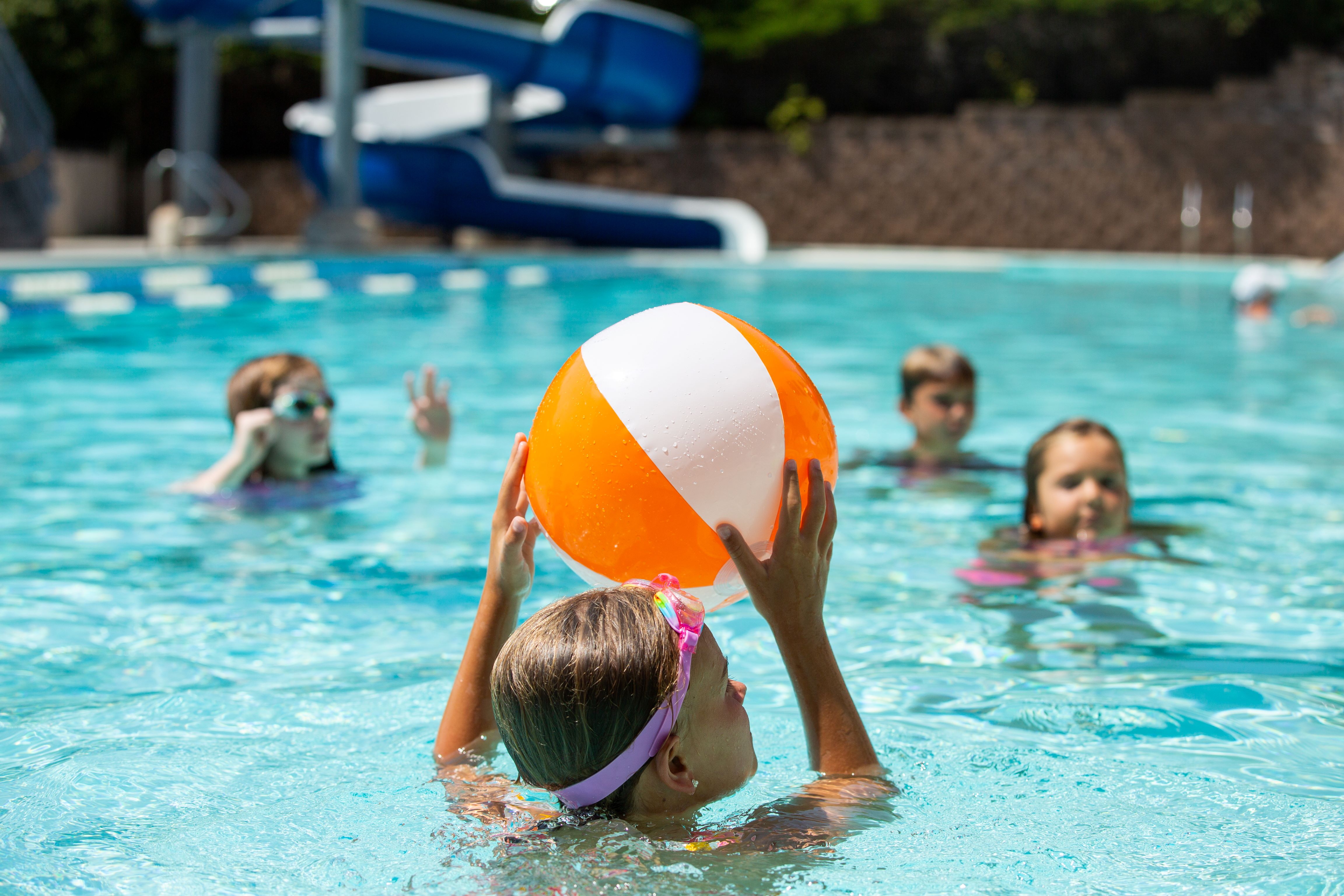 Kids playing in pool with beach ball 